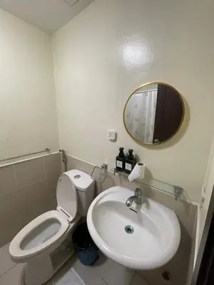 a bathroom with a toilet and a sink and a mirror at A Venue Residences 2403 in Makati