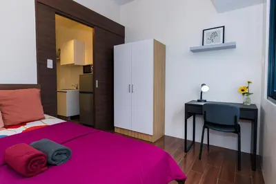 a bedroom with a pink bed and a desk at Suite Life Makati Vibes Views Relaxation 3870 in Manila