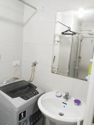 a white bathroom with a sink and a mirror at Maria's staycation in Manila