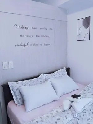 a bedroom with a bed with a quote on the wall at Maria's staycation in Manila