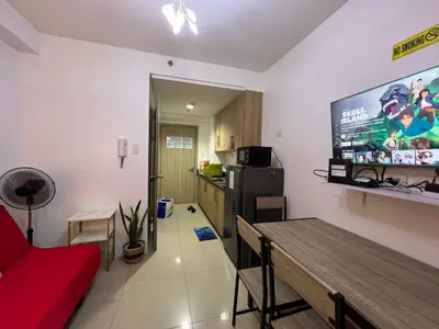a living room with a red couch and a tv on the wall at Apartments at Shore 1 Residences MOA Pasay Near Airport in Manila