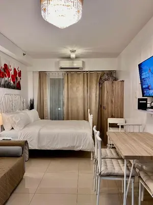 a bedroom with a large bed and a table and chairs at Apartments at Shore 1 Residences MOA Pasay Near Airport in Manila
