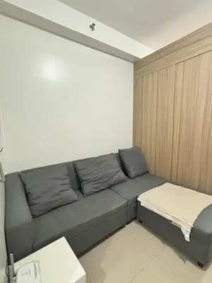 a living room with a gray couch in a room at Cozy Condo Near MOA & Airport in Manila