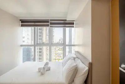 a white bed with a large window in a room at Mystay25V-ParksuitesTower1 in Manila