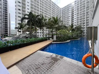 a hotel swimming pool with palm trees and buildings at Casa JYD at Shore Residences - Mall of Asia in Manila