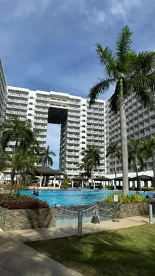 a large building with a swimming pool and a palm tree at Dawn Haven Staycation in Manila