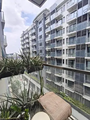 a balcony with plants and a large building at LDN II Palm Tree Villa NAIA 3 in Manila