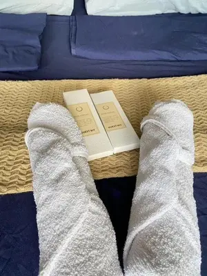 a person wearing white socks on a bed with a book at Air Residences in Manila