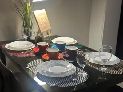 a table with plates and cups and wine glasses at TravelersChoiceCondominium in Manila