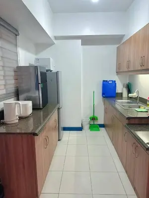 a kitchen with wooden cabinets and a stainless steel refrigerator at Torre De Manila in Manila