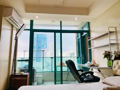 a bedroom with a bed and a desk and a window at Seaview unit in Manila