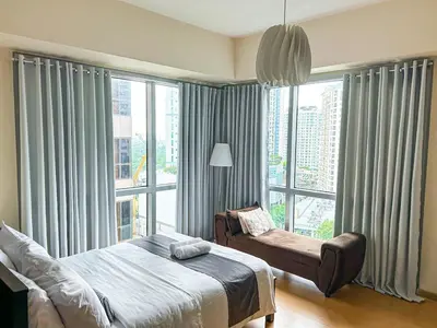 a bedroom with a bed and a chair in front of a window at Budget City View w Pool Access in BGC Taguig City in Manila