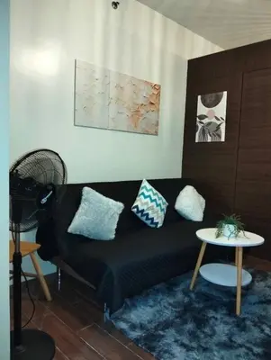 a living room with a black couch and a table at Comfortable & Peaceful for You #4806 in Manila