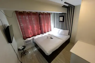 a small room with a bed and a window at Jardin Oriental Suites Ubelt Manila in Manila