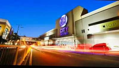 a city street at night with a car dealership at The Destination in Manila