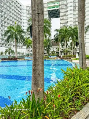a large swimming pool with palm trees and buildings at 1442 Air Condo Signature Stay Modern 1BR w Balcony in Manila