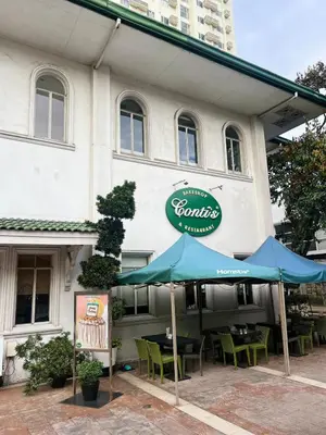 a restaurant with tables and umbrellas in front of it at High and Cozy in Manila