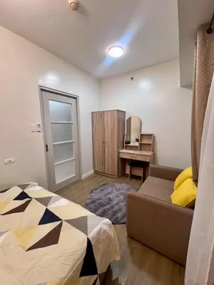 a bedroom with a bed and a couch and a desk at High and Cozy in Manila