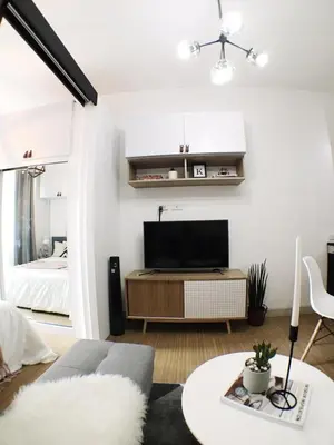 a living room with a couch and a tv on a wall at Airy condo w balcony, Netflix, 3 pools, sleeps 3 in Manila