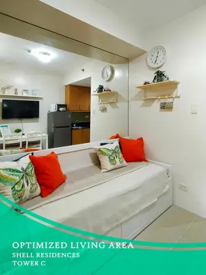 a living room with a couch and a clock on the wall at GV Holiday Homes - Shell Residences MOA - Cozy 1BR Apartment in Manila