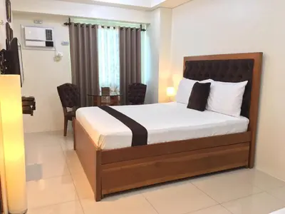 a bedroom with a bed and a table with a chair at Studio Unit at The Beacon Makati in Manila