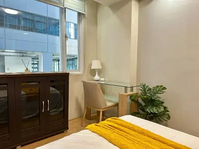 a bedroom with a bed and a desk and a window at Spacious 1BR Condo with 300mbps WiFi in BGC in Manila
