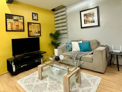 a living room with a couch and a tv at Spacious 1BR Condo with 300mbps WiFi in BGC in Manila