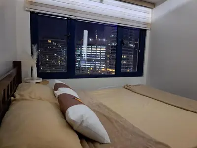 a bedroom with a bed with a view of a city at Air Residences in Manila