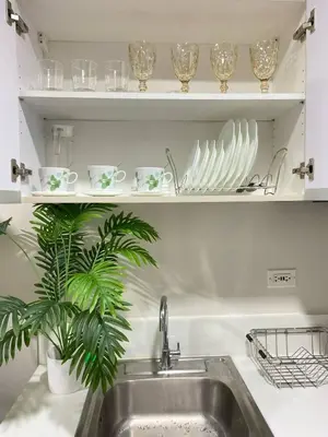 a kitchen sink with plates and glasses on shelves at Air Residences in Manila
