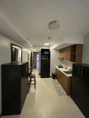 a kitchen with black cabinets and a black refrigerator at Makati City Antel Spa Residences 2306 in Manila