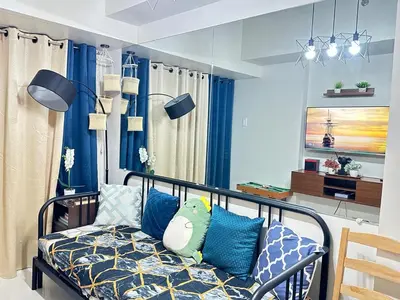 a bedroom with blue curtains and a bed with pillows at Casa De Ciudad - Shore Residences MOA PASAY in Manila