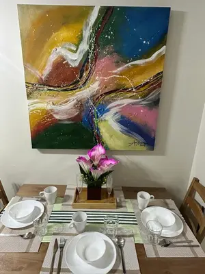 a dining room table with a painting on the wall at Casa De Ciudad - Shore Residences MOA PASAY in Manila