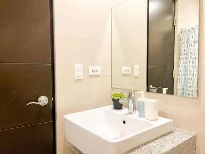 a bathroom with a white sink and a mirror at Prime 1BR Condo in the Heart of BGC #upt12j in Manila