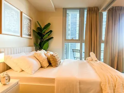 a bedroom with a white bed with pillows and a window at Prime 1BR Condo in the Heart of BGC #upt12j in Manila