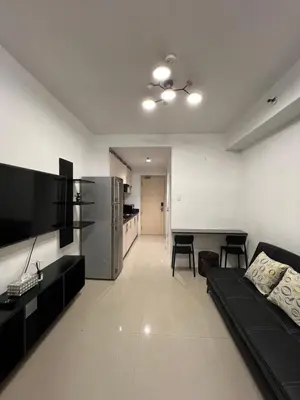 a living room with a black couch and a table at Sea Residences Fireworks View - Reynil in Manila