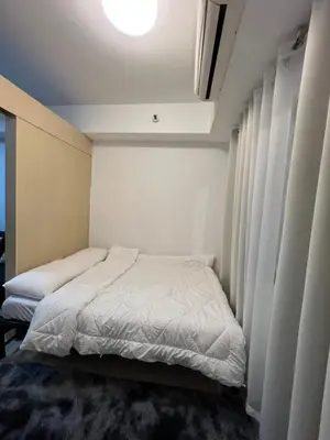 a small bedroom with a white bed and curtains at Sea Residences Fireworks View - Reynil in Manila