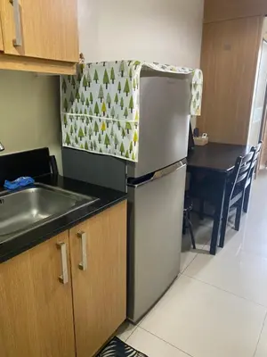a kitchen with a refrigerator and a sink and a table at Sebby's staycation at Shell MOA in Manila