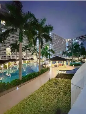 a large swimming pool with palm trees in a building at Sebby's staycation at Shell MOA in Manila