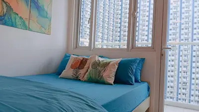 a bed with pillows in a room with windows at 1BR Condotel with Balcony at SM Light Residences #LT04-1 in Manila