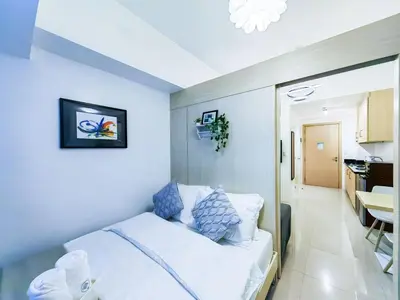a bedroom with a white bed and a kitchen at 1BR Condotel with Balcony at SM Light Residences #LT06-1 in Manila