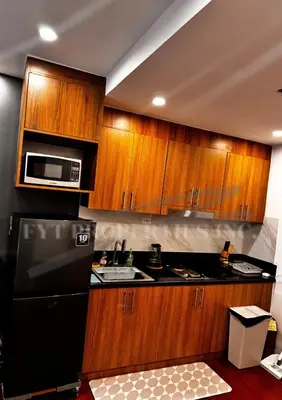 a kitchen with wooden cabinets and a black refrigerator at Lux Staycation at Shore 3, MOA in Manila