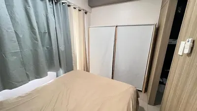 a small bedroom with a bed and a glass door at STARR VACATION Condo in Manila