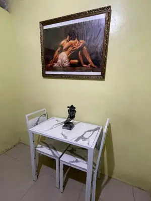 a white table with two chairs and a painting on the wall at D and A Transient Inn Taguig in Taguig