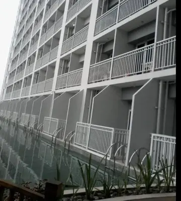 a tall white building with a reflection in the water at La Maison Breeze Residence in Manila