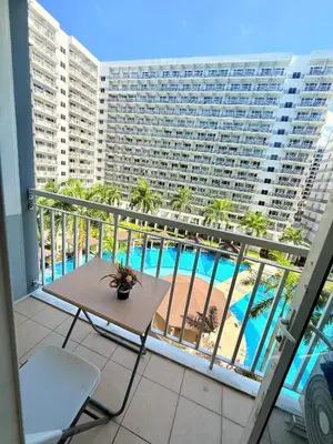 a balcony with a table and a view of a pool at Shell Residences MOA Prime - Paul in Manila