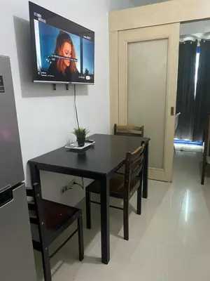 a dining room with a table and a tv on the wall at Ennu staycation Near Moa in Manila