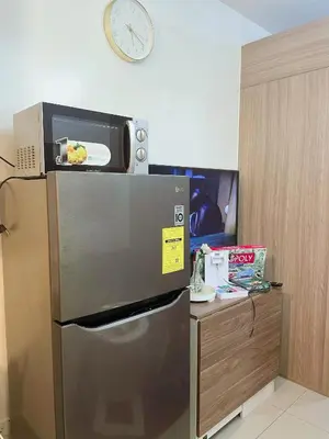 a microwave sitting on top of a refrigerator at On The Shores - Staycation in Manila