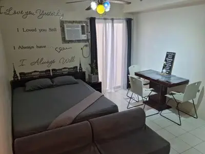 a bedroom with a bed and a desk and a couch at Alabang Staycation Sucat in Manila