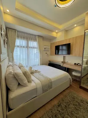 a bedroom with a bed with a desk and a television at Manila Bay Suite near PICC in Manila