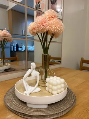 a table with a vase with pink flowers and two dolls at Vista gracia staycation in Manila